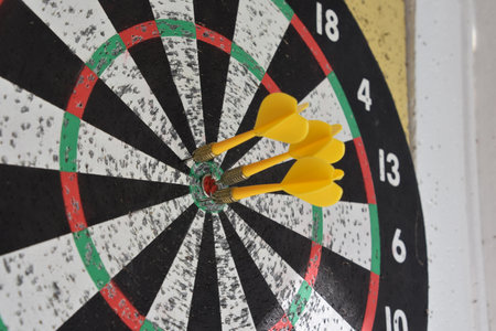Three yellow darts in a dartboard.