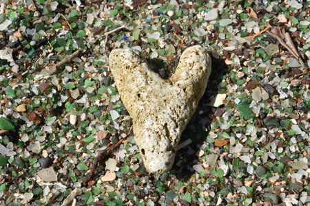 Natural heart shaped stone on a beach filled with sea glass.の写真素材
