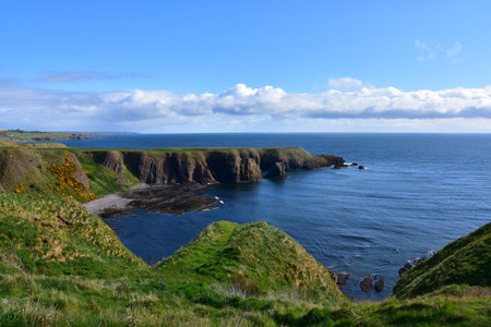 Tall sea cliffs jutting into the ocean around a bay in Scotland.