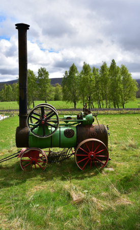 Antique steam engine in a field for agricultural work.