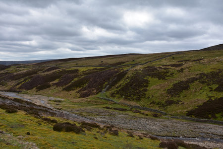 Rolling and tumltuous hills with a small meandering creek in England.