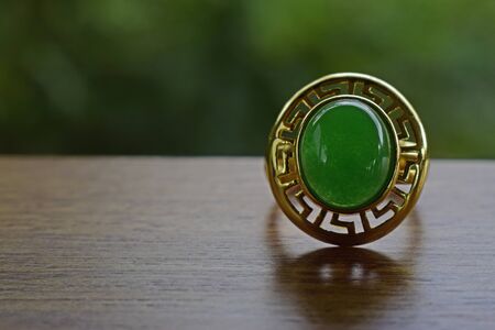 Gold ring decorated with jade Green placed on a wooden floorの写真素材