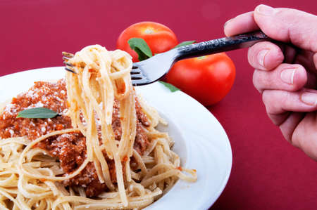 woman's hand holding fork with spaghetti on a plate