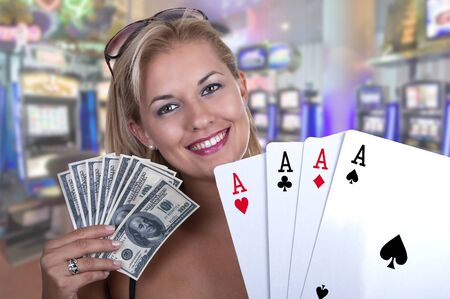Blond Female model smiling while holding a poker hand of four aces and money