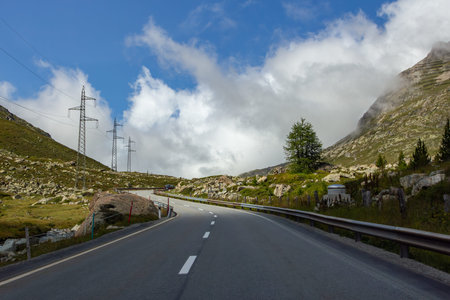 Empty Alpine Pass Road with Power Line Pylons in Swiss Mountains