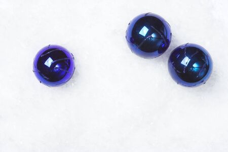 Three dark blue baubles on artificial snow, room for copy.の写真素材