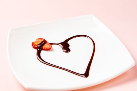 Heart made of chocolate topping and a slice of strawberry. Shallow dof, focus is on a strawberry.の写真素材