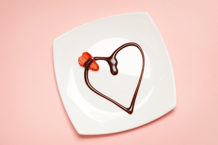 Valentine's day dessert - heart made of chocolate topping and a slice of strawberry, view from above.の写真素材