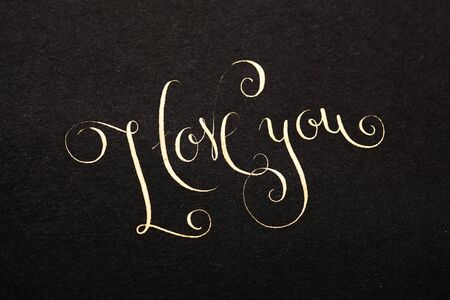 I love you written by hand with golden ink over black paper.の写真素材