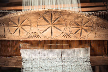 An old hand-weaving vintage wooden loom being used to make fabric. Traditional european solar symbols on it's panel.の写真素材