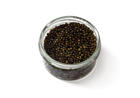 Glass jar of black caviar isolated over white. Natural sturgeon luxury delicacy closeup. Seafood delicatessen appetizer.の写真素材