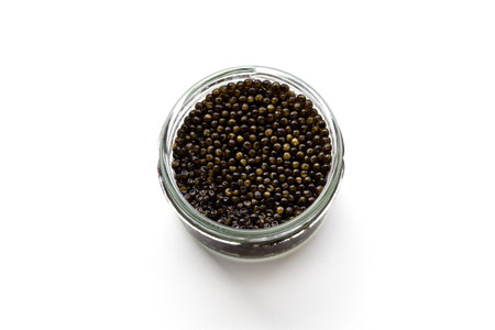 Glass jar of black caviar isolated over white. Natural sturgeon luxury delicacy closeup. Seafood delicatessen appetizer.の写真素材