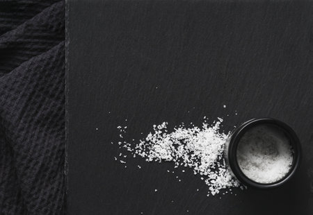 Organic sea white salt and a jar on a black slate stone background. Concept of cooking natural...