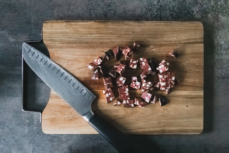 Knife and chopped sausage on a wooden chopping board. Food flat lay, top view. German traditional...