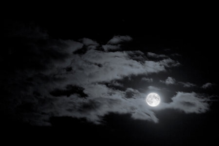 Full Moon glowing in the night, clouds in the sky.の写真素材