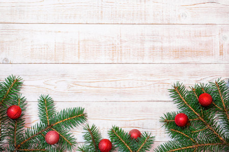 Christmas background - fir branches and red ornaments on a white wood table. Flat layout, top view...