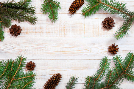 Christmas background - fir branches and pine cones on a white wood table. Flat layout, top view composition border with copy space.の写真素材