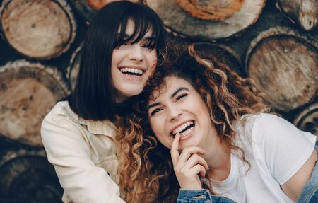 The close up photo of two smiling gorgeous women posing on a woody backgroundの写真素材