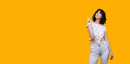 A nice view of a charming caucasian lady eating and stretching a gum on a yellow wall with freespaceの写真素材