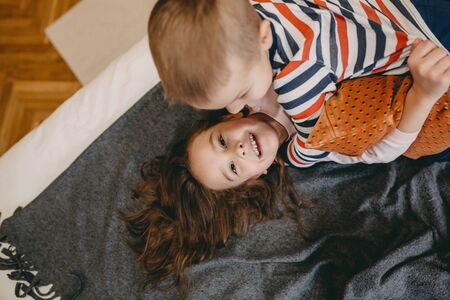 Upper view portrait of two playing on the floor siblings , smiling and looking for adventuresの写真素材
