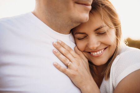Lovely caucasian woman lying on her husband and embracing him during a perfect sunshineの写真素材