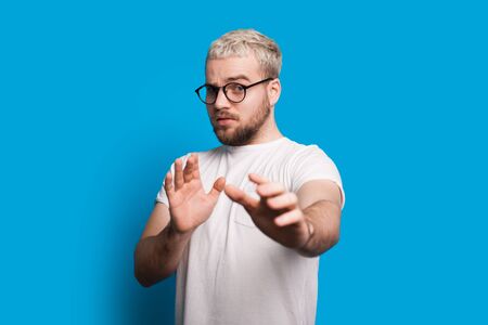 Caucasian man with blonde hair and short beard is looking through eyeglasses and gesturing fear...