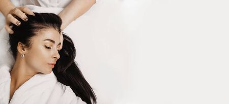 Upper view portrait of a sensual lady with black hair and closed eyes who is lying while a spa procedureの写真素材