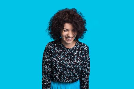 Lovely curly haired caucasian woman smiling cheerfully on a blue background