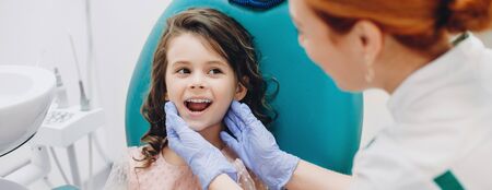Lovely kid smiling to the doctor while having a teeth surgery at the stomatologyの写真素材