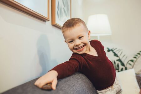 Blonde caucasian boy playing on the sofa with a car driving happilyの写真素材