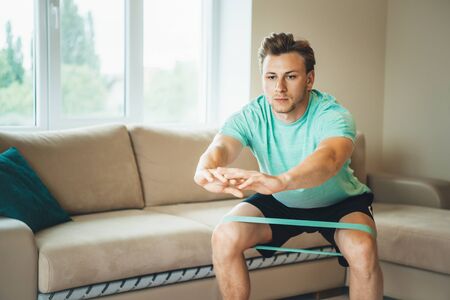 Caucasian man with blonde hair warming up with elastic bands before doing morning exercisesの写真素材