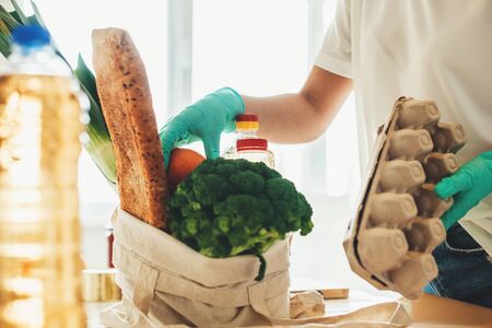 Caucasian woman in kitchen unboxing products bought via online delivery during lockdownの写真素材