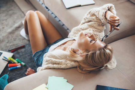 Tired blonde woman sitting on floor and homeschooling using a laptopの写真素材