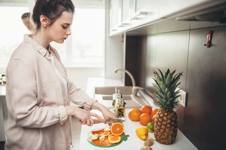 Young caucasian couple preparing a fruit salad together in the kitchen slicing fruits