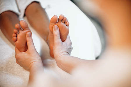 Close up photo of a foot massage procedure done at a wellness center by a masseurの写真素材