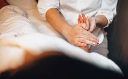 Caucasian lady lying and having hand massage procedure covered with a white towel at spa centerの写真素材