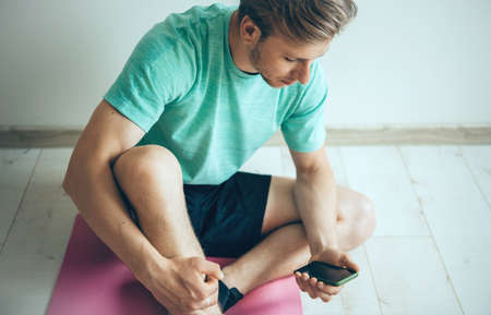 Blonde caucasian man wearing sportswear on the floor is relaxing while doing fitness at home and...