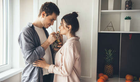 Lovely young couple drinking a mojito at home in the kitchen looking at each otherの写真素材