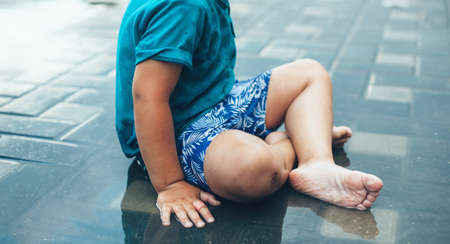 Side view photo of a caucasian boy lying wet in water after rain in the yardの写真素材