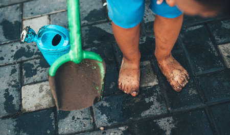 Dirty caucasian kid playing with toys at home in the garden with water is ready for a bath