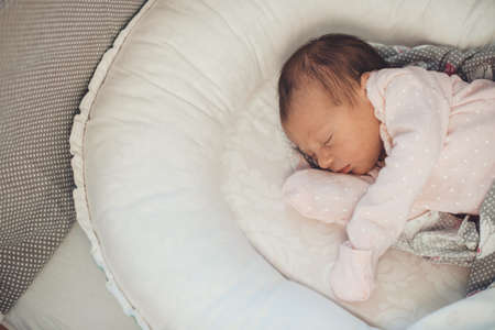 Upper view photo of a caucasian newborn baby sleeping in bed at home wearing white clothesの写真素材