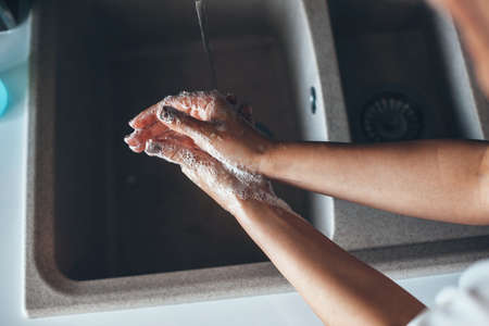 Upper view photo of a caucasian woman washing her hands with a soap at homeの写真素材