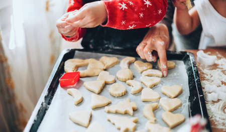 Close up photo of a caucasian family in holiday clothes making christmas cakes of different forms