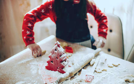 Caucasian girl preparing food for christmas holidays using a lot of flour on table while wearing santa clothesの写真素材