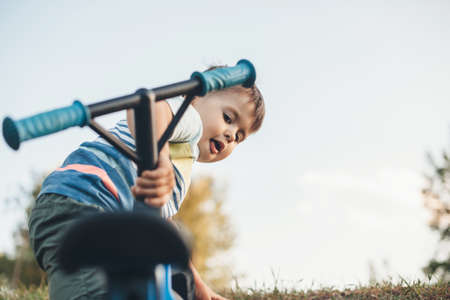 Small caucasian boy picking up his bicycle after falling down during a walk in the countryside