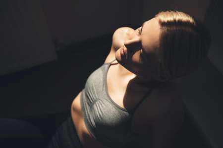 Upper view photo of a caucasian woman in sportswear having a break on the floor while doing home...