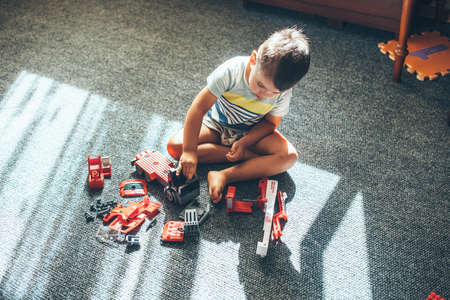 Upper view photo of a caucasian boy playing on the floor with constructor car and toysの写真素材