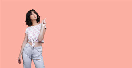 Brunette woman is chewing and stretching a gum with finger posing in fashionable clothes on a studio...