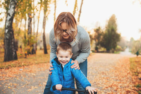 Caucasian woman and her son riding the bike in park teaching himの写真素材