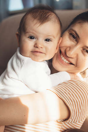 Close up photo of a caucasian mother and her daughter smiling at camera while embracingの写真素材